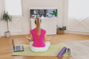 Girl doing yoga with roller at home in front of aquarium